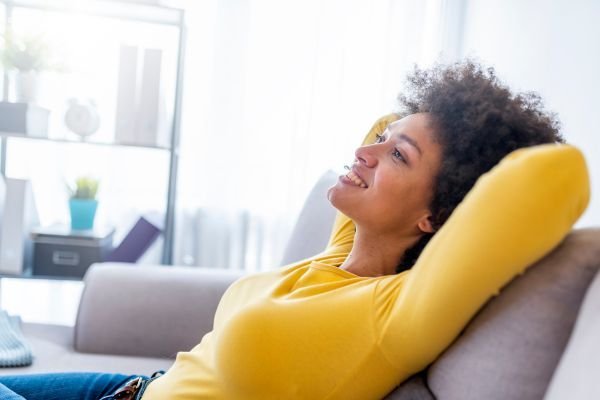 Mulher descansando no sofá depois de estar com a casa organizada sem estresse.